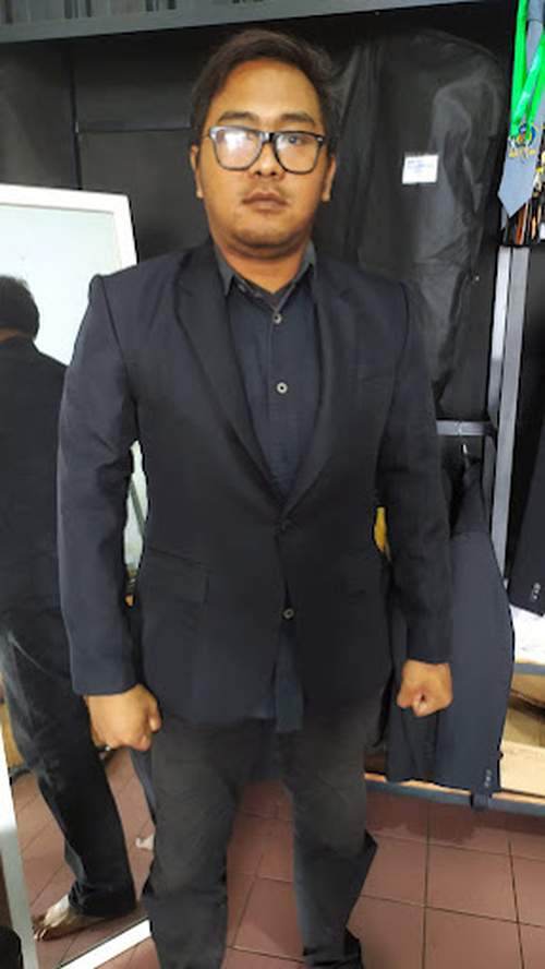 Pelanggan MENSWEAR Mens Apparel mencoba jas custom hitam di ruang fitting